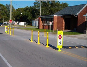 A street with yellow posts and a stop sign.